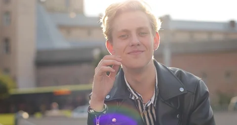 Young blond guy straightens his hair and laughs. the sun shines bright. good Stock Footage 126576499