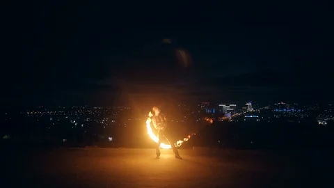 Young blond male does fire dance with two torches, spins torches at night on Stock Footage 105213327