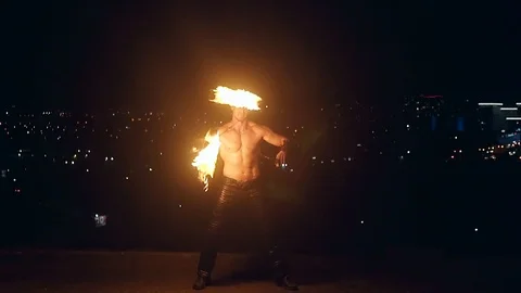 Young blond male does fire dance with two torches, spins torches in the middle Stock Footage 105214376
