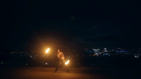 Young blond male does fire dance with two torches, spins torches in the middle Stock Footage 105219972