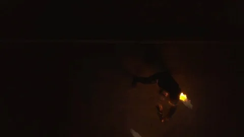 Young blond male does fire dance with two torches, spins burning torches. Aerial Stock Footage 105220973