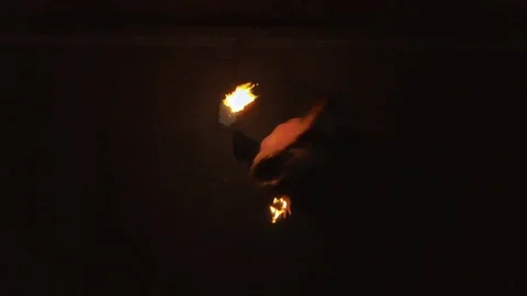 Young blond male does fire dance with two torches, spins burning torches. Aerial Stock Footage 105220995