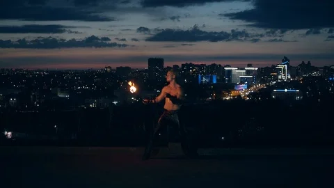 Young blond male does tricks with fire, breaths fireball in the middle of the Stock Footage 105213015