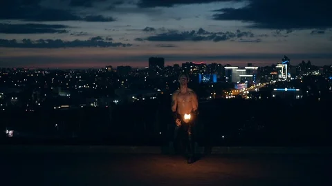 Young blond male does tricks with fire, Male faces camera, breathes fire kneels Stock Footage 105213132
