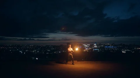 Young blond male does tricks with fire, breaths fireball in the middle of the Stock Footage 105213174