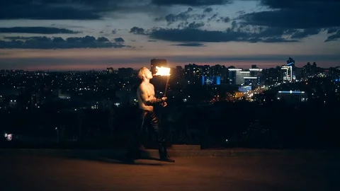 Young blond male does tricks with fire, breaths fire in the middle of night with Stock Footage 105213509