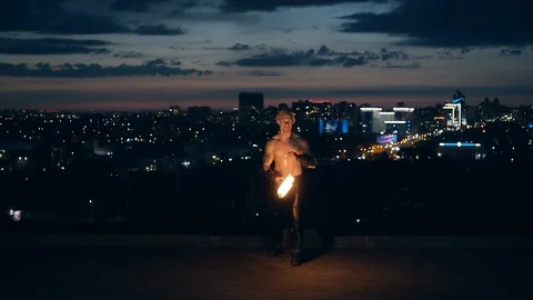 Young blond male does tricks with fire, Male kneels while breathing fire making Vídeo Stock 105213561