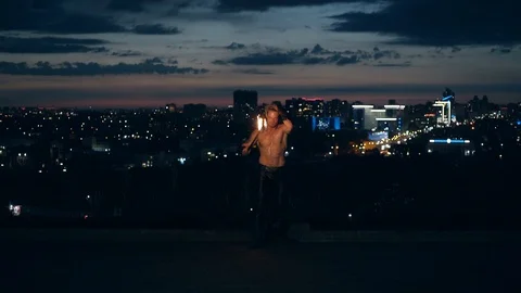 Young blond male does tricks with fire, breaths fire. Male breaths out large Stock Footage 105213597