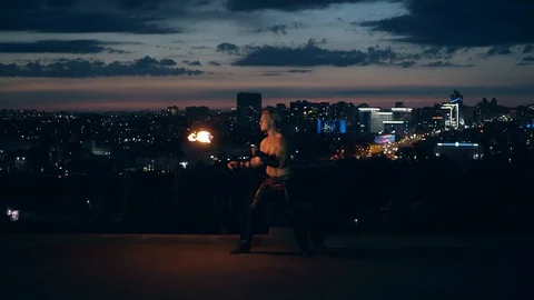 Young blond male does tricks with fire, Male kneels while breathing fire making Stock Footage 105219143