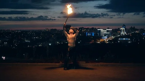 Young blond male does tricks with fire, breaths fire in the middle of the night Stock Footage 105219265