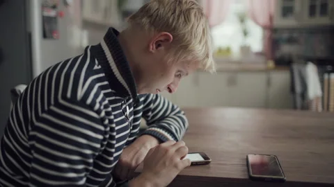 Young Blond Man Sits Kitchen Home And Uses Smartphone For Communication 스톡 동영상 143797106