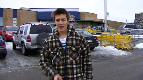 The Young Blond Man Speaks to the Camera in a Supermarket Parking Lot Stock Footage 154214863