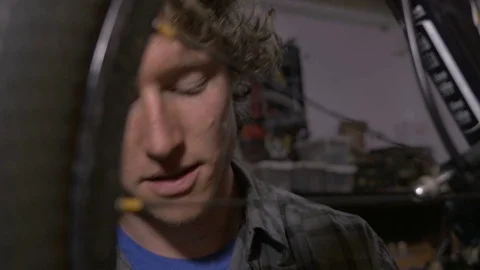 A young blond man working on a bicycle in a garage Stock Footage 69908705
