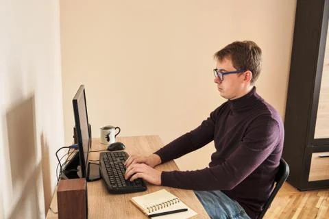 Young blond man working at computer at home Stockfoto's