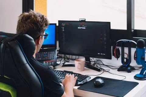 Young blond man working sitting in his desk chair at home at his computer. Stock Photos
