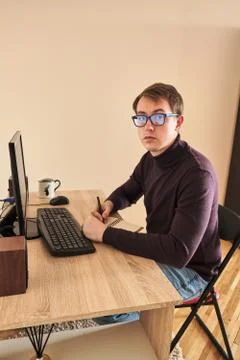 Young blond millennial working at computer drinking coffee at home Stockfoto's