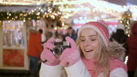Young blond smiling female in warm clothes with retro film camera shooting a Stock Footage 101015563