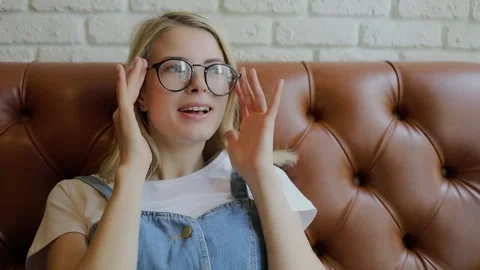 Young blonde adjust glasses during sits in cafe. Stock Footage 299631442