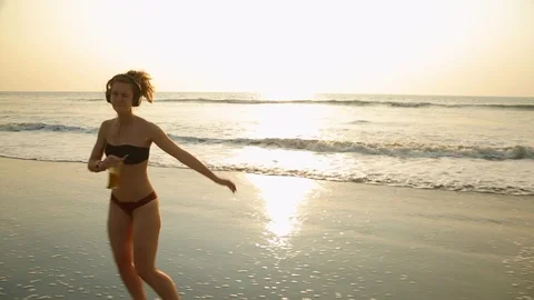 A young blonde on beach dancing spinning and looking at the camera Stock Footage 93565233