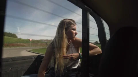 Young blonde blogger woman sitting in the back of a truck with clear blue sky in Stock Footage