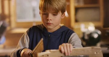 Young blonde boy is for the first time working with wood in a cinematic looki Stock Footage 85809362