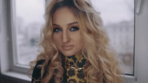 The young blonde, curly, with a bright make-up looks confidently ahead, with a Stock Footage 157683575