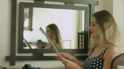 Young blonde flipping through the menu in a stylish hotel room then calling and Stock Footage 85036018