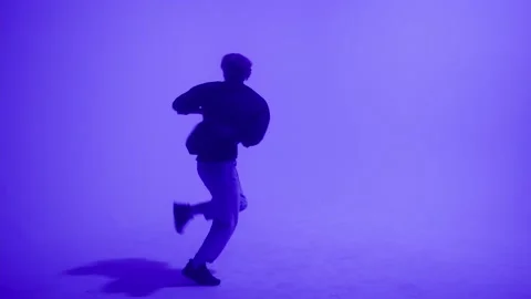 Young blonde guy dancing modern choreography on purple background in studio Stock Footage 156057802