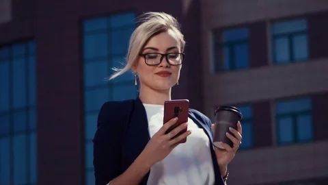 A young blonde in a light blouse and a dark jacket stands near an office Stock Footage 94483786
