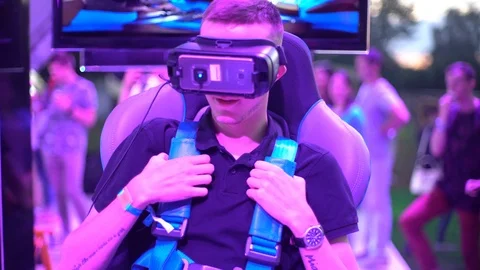 A young blonde man sitting testing the helmet of virtual reality vr oculus Stock Footage 118140176