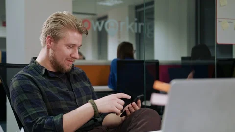 A Young Blonde Man Using a Phone in the Office Stock Footage 86358827
