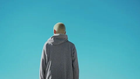 Young blonde man waves goodbye or hello to sky Stock Footage 104220309