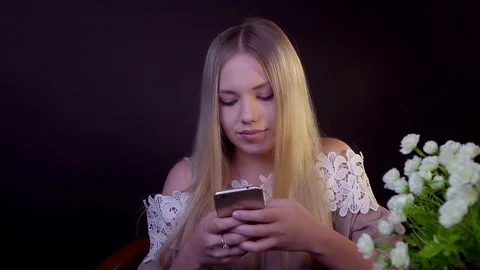 Young blonde is smiling on a black background. It prints a text message on the Stock Footage 79246922