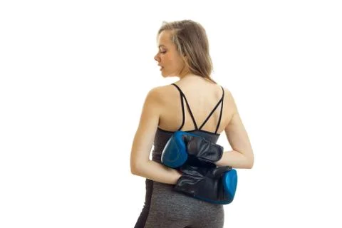 Young blonde stands back to the camera and holds her arms behind her back in Stock Photos
