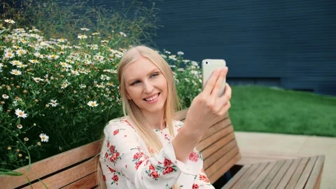 Young blonde woman smiling using smartphone on mall living roof bench Video stock 340565507