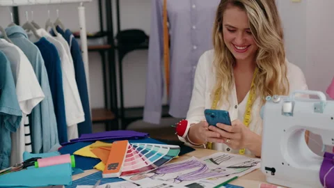 Young blonde woman tailor using smartphone looking color test at tailor shop Stock Footage 221108790