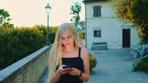 Young blonde woman using smartphone in European outdoor courtyard Video stock 342333014