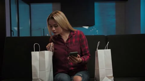 Young blonde women checking orders for goods and packaging shopping bag sitting Stock Footage 225654533