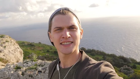 Young blue-eyed guy makes a selfie on the background of nature, sea, rocks Stock Footage 101501510