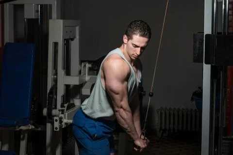 Young bodybuilder doing heavy weight exercise for triceps with cable Stock Photos