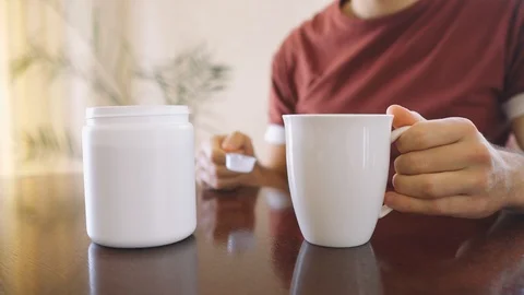 Young bodybuilder man makes protein mixture at home while sitting at the table. Stock Footage 125637262