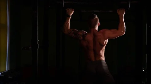 Young bodybuilder training in a gym. Doing pullups. 60 to 24fps 4K Stock Footage 74339320