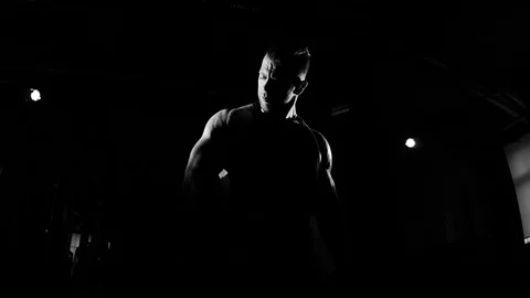 Young bodybuilder training in a gym. Dramatic black and white footage Видео 74313053