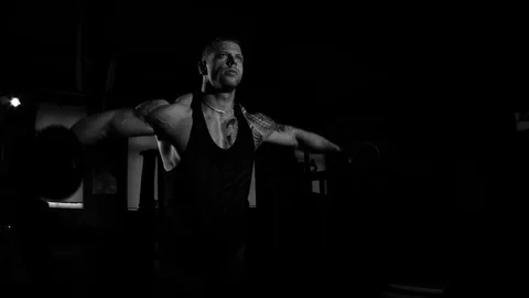 Young bodybuilder training in a gym. Dramatic black and white footage Видео 74313211