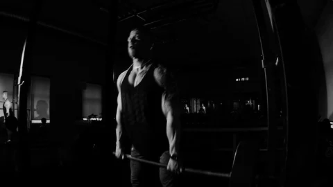 Young bodybuilder training in a gym. Dramatic black and white footage Stock Footage 74313274