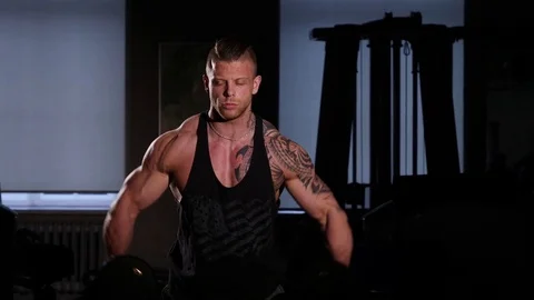 Young bodybuilder training in a gym with dumbbels. 60 to 24fps 4K Stock Footage 74339000
