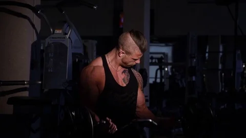 Young bodybuilder training in a gym with EZ barbell. 60 to 24fps 4K Stock Footage 74312934