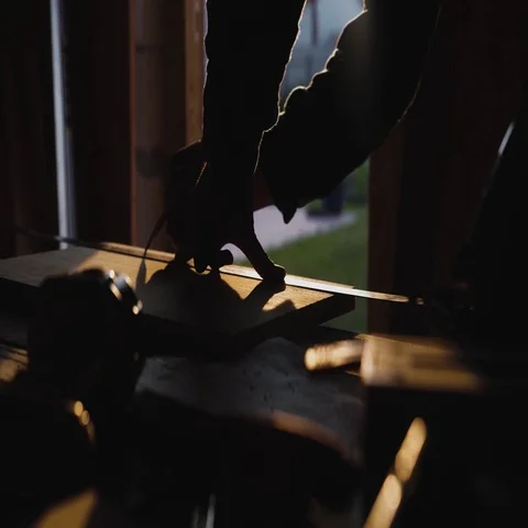 Young bold carpenter with moustache. circular saw cutting piece of wood. sun Stock Footage 69539956