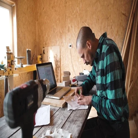 Young bold carpenter with moustache drawing in his workshop Stock Footage 69532847
