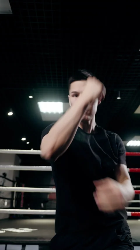 A young boxer with an athletic physique punches at the camera. Vertical video Stock Footage 260146923